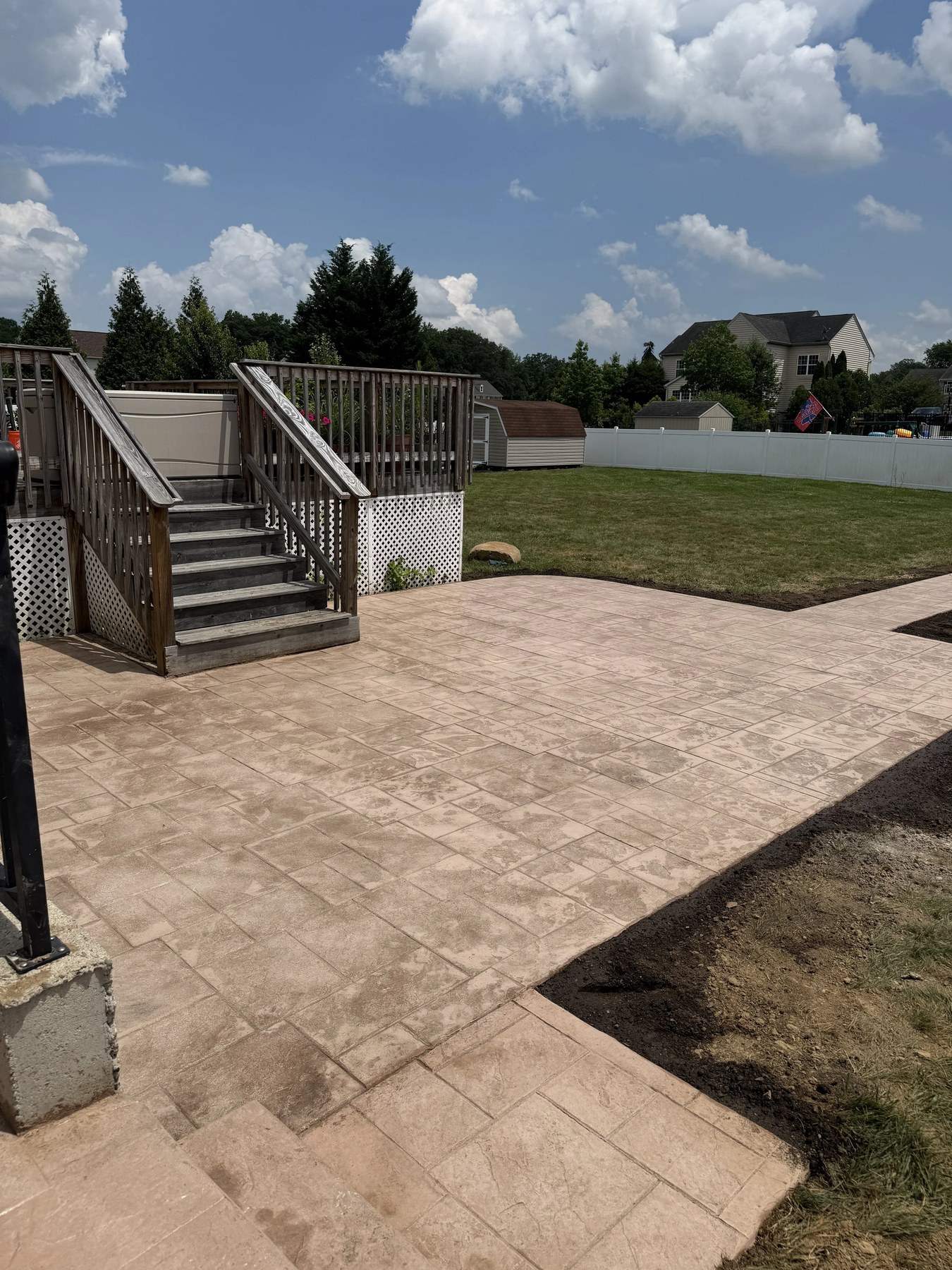 Backyard concrete patio with wooden steps and lawn in Wilmington, DE