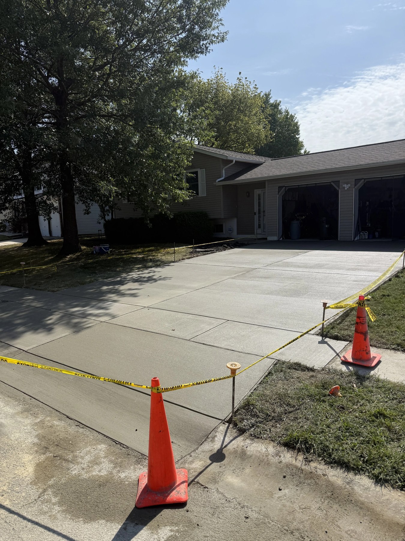 Freshly poured concrete driveway section cordoned with cones and caution tape in New Castle, DE